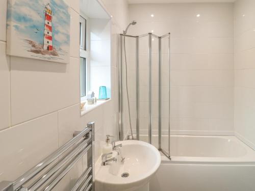 a white bathroom with a sink and a shower at Church View Cottage in Rugeley