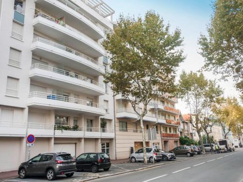 un edificio de apartamentos blanco con coches estacionados frente a él en Apartment Le Palma-2 by Interhome, en Arcachon