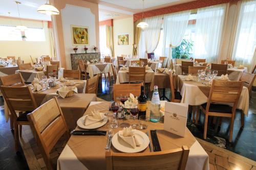 restauracja z białymi stołami i krzesłami oraz stolarką w obiekcie Hotel Fai w mieście Fai della Paganella