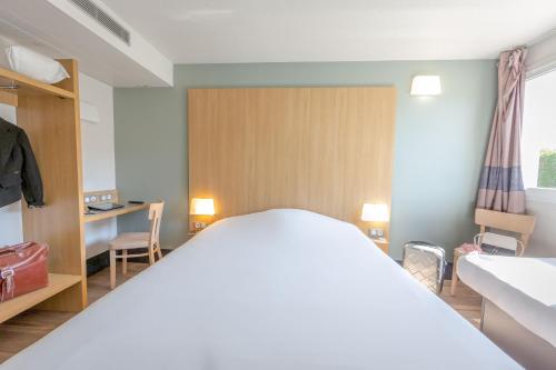 a bedroom with a large bed and a desk at B&B HOTEL PERPIGNAN Nord Aéroport in Perpignan