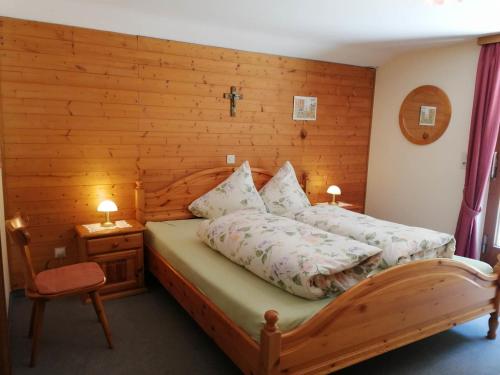 een slaapkamer met een bed en een houten muur bij Ferienwohnung Waldhaus in Sankt Gallenkirch