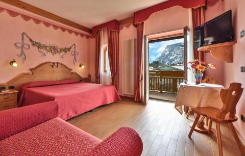 a bedroom with a bed and a television and a balcony at Hotel Fai in Fai della Paganella
