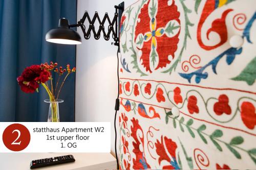 a lamp next to a table with a vase of flowers at statthaus - statt hotel in Cologne