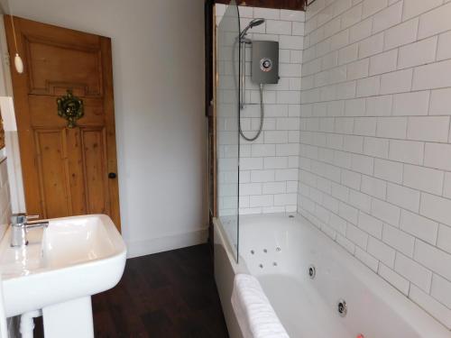a bathroom with a tub and a sink and a shower at The Old Registry guest house in Haworth