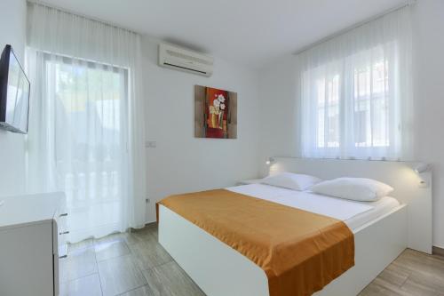 a white bedroom with a bed with white walls and windows at Stipe Residence in Podstrana