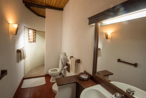 La salle de bains est pourvue de toilettes, d'un lavabo et d'un miroir. dans l'établissement Baobab Sea Lodge, à Kilifi