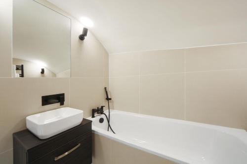 a white bathroom with a sink and a bath tub at Newly Refurbished Flat With Patio. By Hyde Park in London