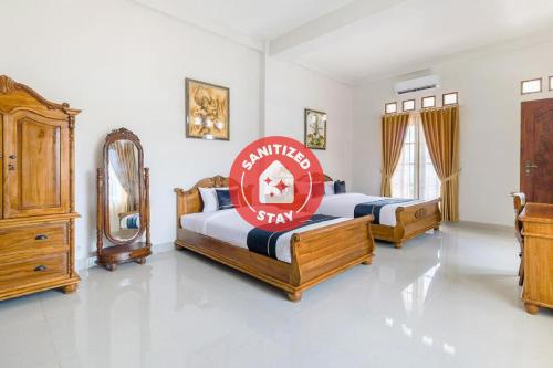 um quarto com duas camas e um espelho em SUPER OYO Collection O 3468 Ndalem Gusti Ayu em Yogyakarta