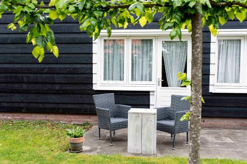 three chairs and a table in front of a house at Hofstede Villetta in Zonnemaire