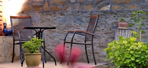 2 sillas y una mesa frente a una pared de piedra en Illés Vendégház, en Keszthely