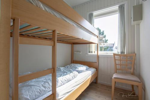 a bedroom with bunk beds with a chair and a window at Hotel Tannishus in Bindslev