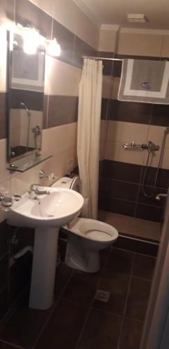 a bathroom with a white toilet and a sink at TETYK Keramoti Hotel Apartments in Keramotí