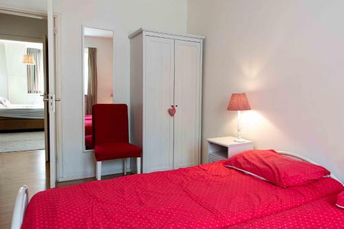 a bedroom with a red bed and a red chair at Hofstede Villetta in Zonnemaire