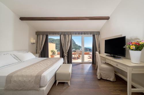 a bedroom with a bed and a desk with a television at Boutique Hotel Torre Di Cala Piccola in Porto Santo Stefano