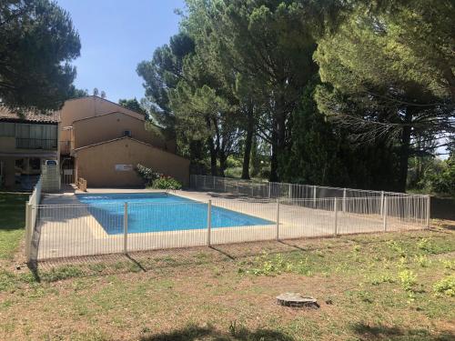 einen Zaun um einen Pool vor einem Haus in der Unterkunft Appartement 239 Les Salicornes in Arles
