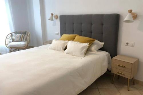 1 dormitorio con 1 cama blanca grande y 1 silla en Beautiful apartment in Salinetas Beach, en Salinetas