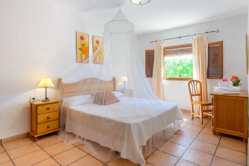 a bedroom with a bed with a mosquito net at Casa Es Pins in Santa Eularia des Riu
