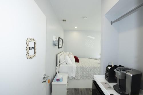 a white bedroom with a bed and a tv at Serene Niagara Inn in Niagara Falls