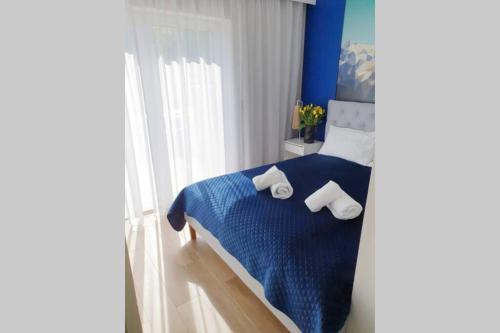 a bedroom with a blue bed with towels on it at RelaxApart - Komfortowy apartament z prywatną sauną in Szczyrk