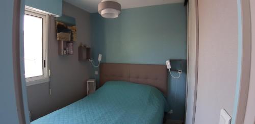 een kleine slaapkamer met een groen bed en een raam bij Appartement 2 min à pied de la mer et du centre ville in Saint-Georges-de-Didonne