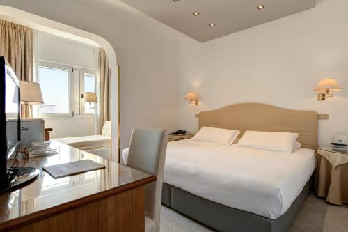 a bedroom with a bed and a desk with a computer at Park Hotel Brasilia in Lido di Jesolo
