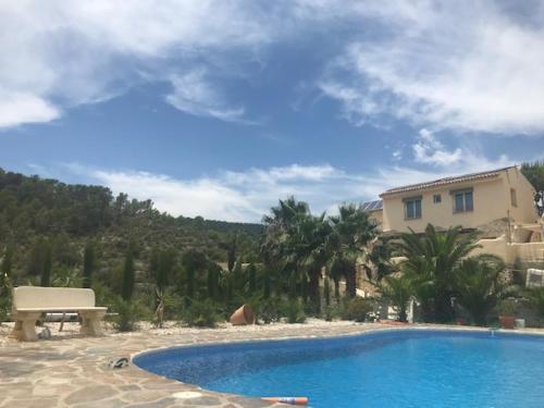 a swimming pool with a bench next to a house at Finca las Estrellas in Relleu