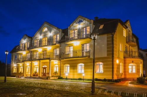 a large yellow building at night with lights at Villa Sylvia in Dźwirzyno