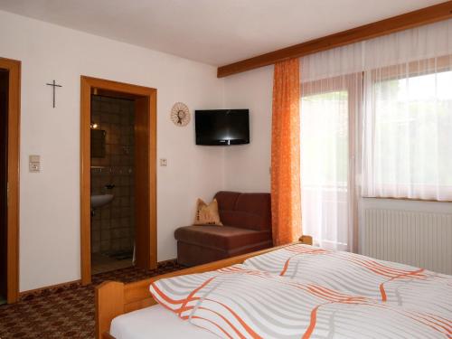 a bedroom with a bed and a couch and a television at Apartment Garni Regina-1 by Interhome in Kappl