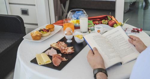 a person reading a book at a table with food at Hotel Niagara in Catanzaro Lido