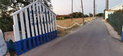 a white fence with a blue fence next to a road at Retiro dos Batudes in Palmela