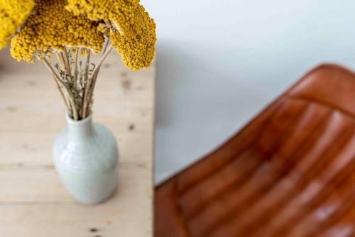 a white vase with yellow flowers sitting on a table at Hofstede Villetta in Zonnemaire