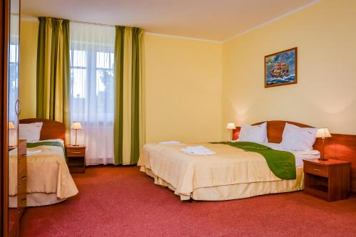 a hotel room with two beds and a window at Villa Sylvia in Dźwirzyno