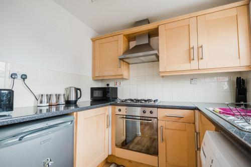 a kitchen with wooden cabinets and a stove top oven at Hullidays - Victoria Dock Residence in Hull