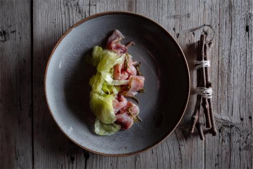 a plate of food with ham and lettuce on a table at Venissa Wine Resort in Burano