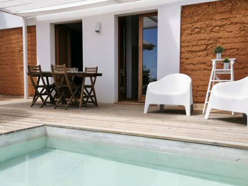 eine Terrasse mit einem Tisch, Stühlen und einem Pool in der Unterkunft BeGuest Casas de Taipa in Lagoa