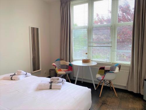 een kamer met 2 bedden, een tafel en een raam bij Studio het Strandhuis KA04 in Vlissingen