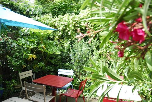 トゥールにあるホテル ミラボーの花の咲く庭園の赤いテーブルと椅子