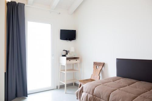 a bedroom with a bed and a chair and a television at Guest House Bella Onda in Tessera