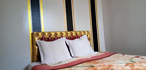 a bed with a gold headboard and white pillows at La casa de Wael in Ifrane