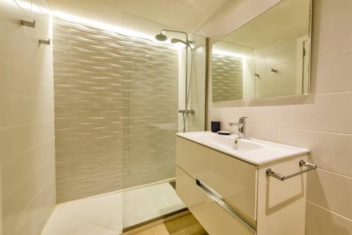 y baño blanco con lavabo y ducha. en Sa Maniga 2C, en Cala Millor