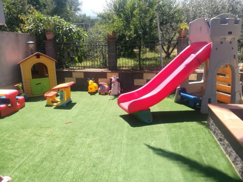 um parque infantil com um escorrega vermelho num quintal em Casa vacanza tra Etna e Taormina Villa Ginevra em Piedimonte Etneo