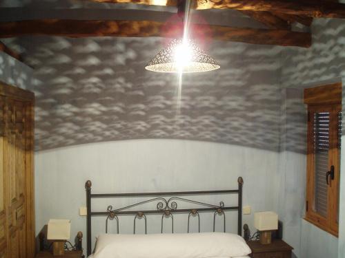 a bedroom with a bed with a light above it at Casa Rural la Ribera in Cabezuela