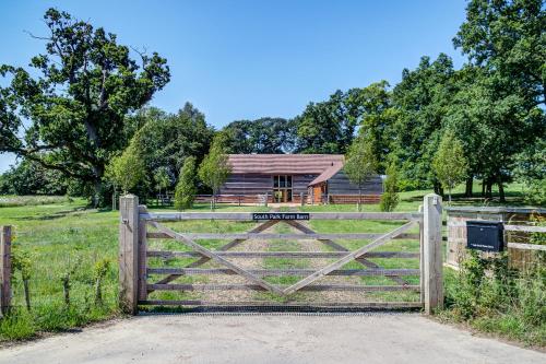 a gate to a barn with a house in the background at South Park Farm Barn in Andover