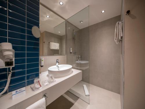 uma casa de banho com um lavatório e um espelho em BEST WESTERN Hotel The K Unterföhring em Munique