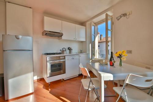 een keuken met een witte koelkast en een tafel met stoelen bij Contempora Apartments - Ca' Brenta Attic in San Fedele Intelvi