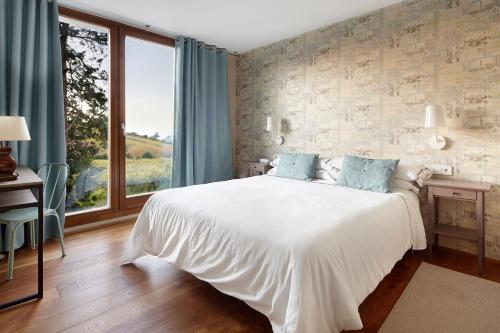 a bedroom with a white bed and a large window at Hotel San Prudentzio in Getaria