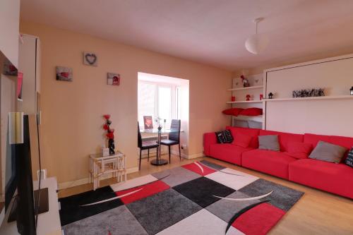a living room with a red couch and a rug at Luxury Studio Apartment in Northolt