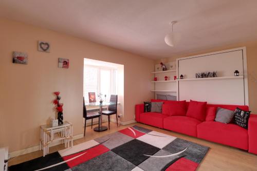 a living room with a red couch and a table at Luxury Studio Apartment in Northolt