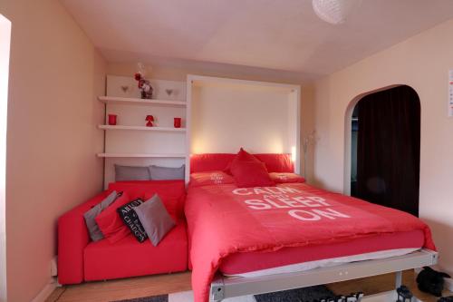 a red bed with a red couch in a room at Luxury Studio Apartment in Northolt