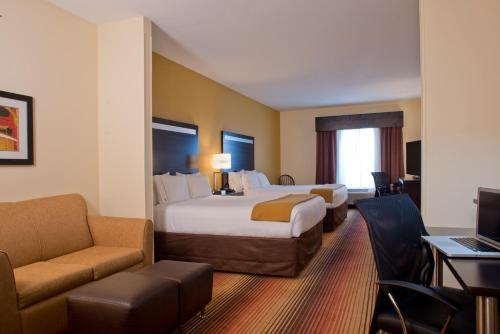 Habitación de hotel con 2 camas, sofá y escritorio. en Holiday Inn Express Hotel & Suites Prattville South, an IHG Hotel, en Prattville